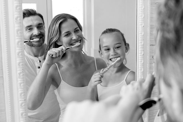 Parents and daughter brushing their teeth in the bathroom.
